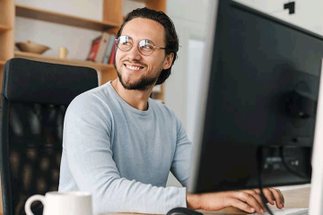 Hombre sonriendo frente a computadora