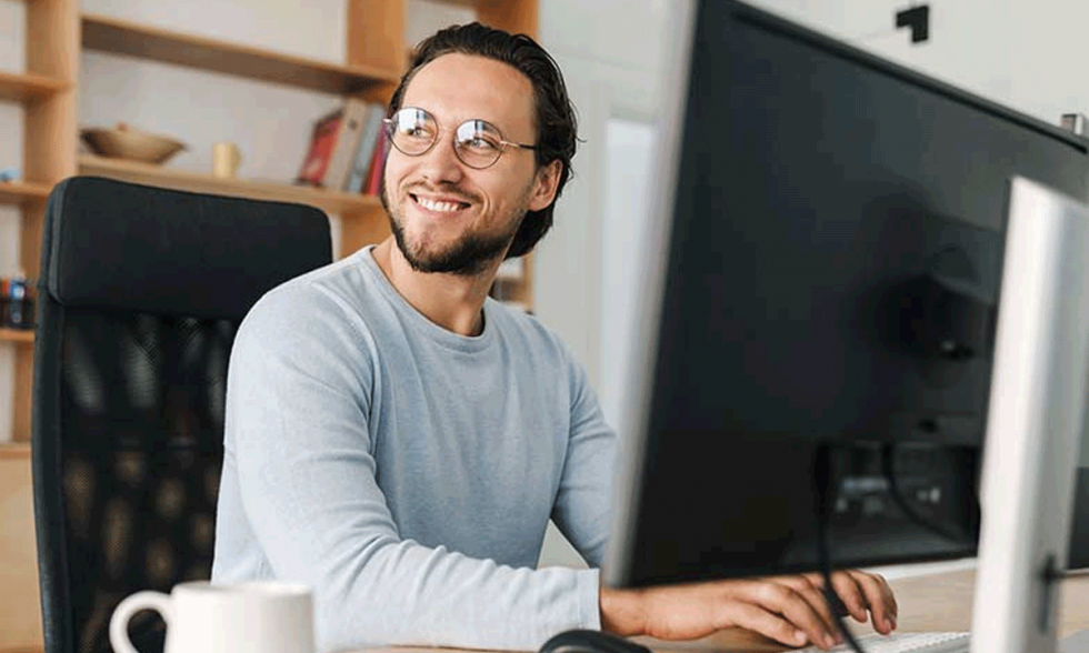 Hombre sonriendo frente a computadora